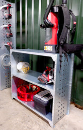 Modular industrial shelving units with various tools and storage containers on them, placed against a green wall in a workspace.